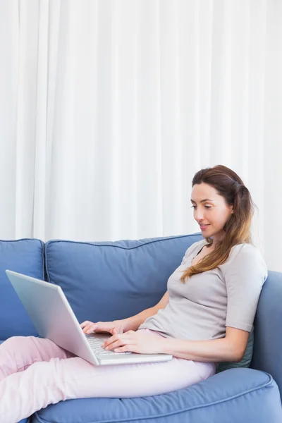 Casual woman using laptop on couch — Stock Photo, Image