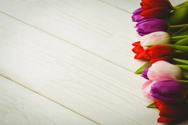 Barevné tulipány na dřevěný stůl — Stock fotografie