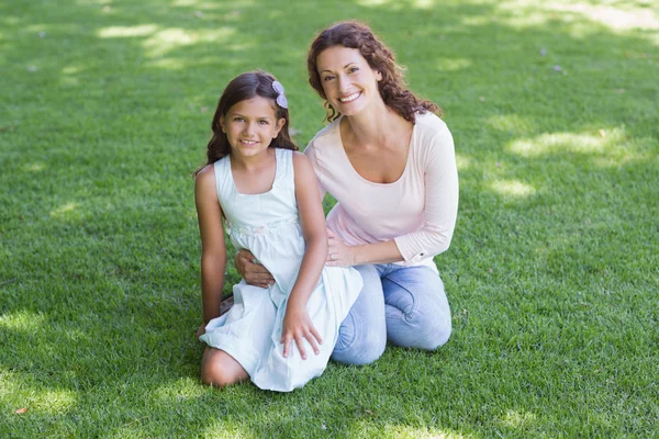 Mère et fille heureuses assises sur l'herbe — Photo