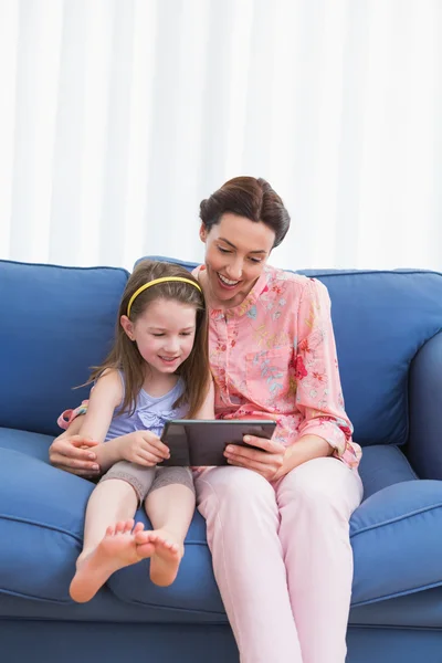 Mother and daughter using tablet on couch — Stock Photo, Image