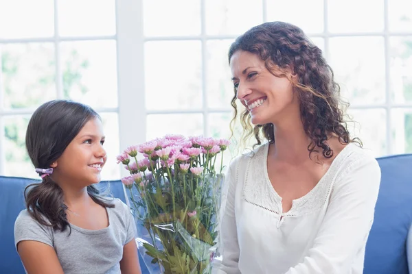 Gelukkig moeder en dochter zittend op de Bank met bloemen — Stockfoto