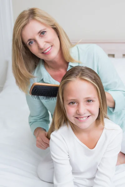 Mère souriante brossant les cheveux de ses filles — Photo