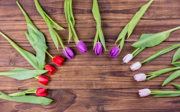 Tulips forming frame on wooden table — Stock Photo, Image