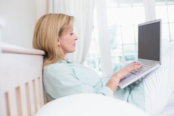 Frau mit Laptop im Bett im Fokus — Stockfoto