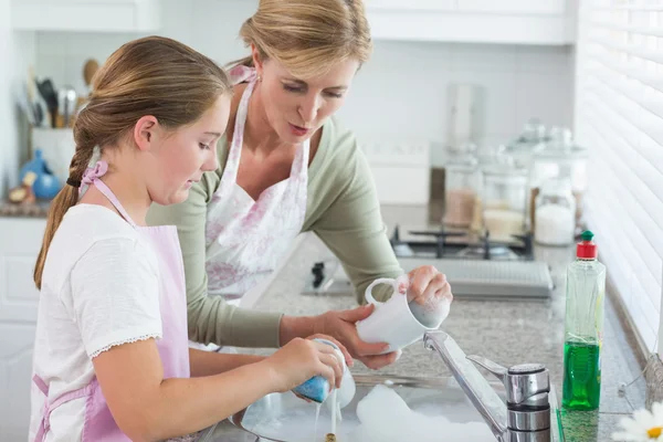 Mother and daughter washing up together Stock Picture
