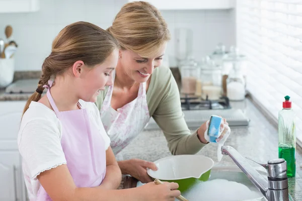 Happy mother and daughter washing up together Stock Photo