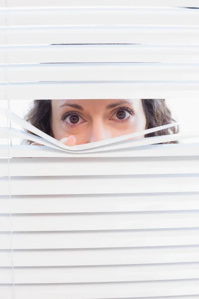 Curious woman looking through blinds — Stock Photo, Image