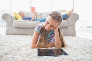 Girl using digital tablet on rug clipart