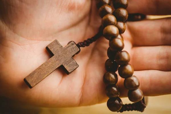 Mano sosteniendo cuentas de rosario de madera — Foto de Stock