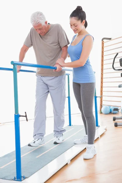 Senior man walking with parallel bars and coach help — Stock Photo, Image