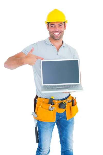 Smiling handyman pointing at laptop — Stock Photo, Image
