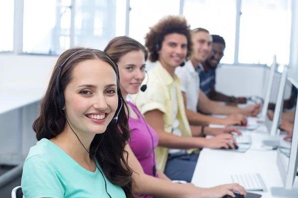 Studenti sorridenti che utilizzano auricolari in classe di computer — Foto Stock
