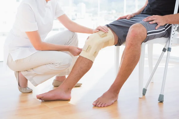 Médico examinando su rodilla paciente —  Fotos de Stock