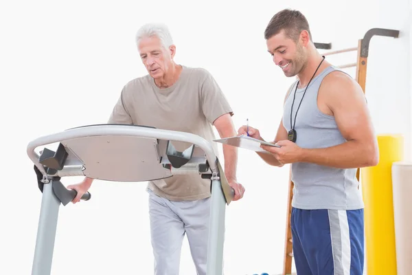 Senior man on treadmill with trainer — Stock Photo, Image