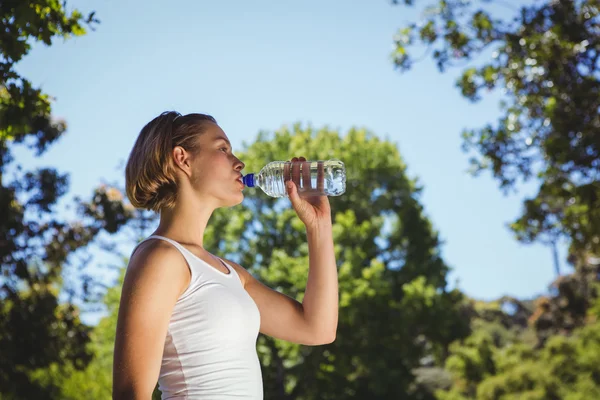 Подходящая женщина пьет воду в парке — стоковое фото