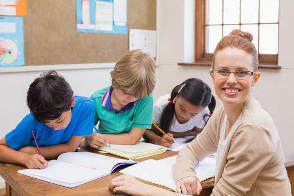 Teacher and pupils working at desk together — Stock Photo, Image