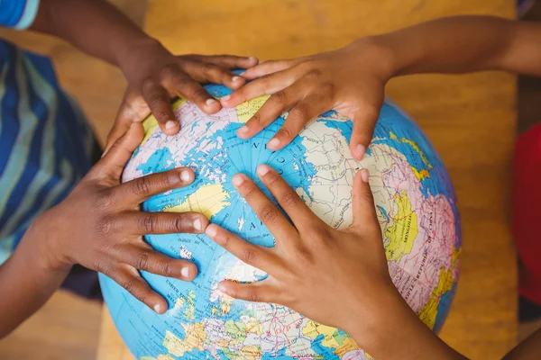 Hands on globe in classroom — Stock Photo, Image