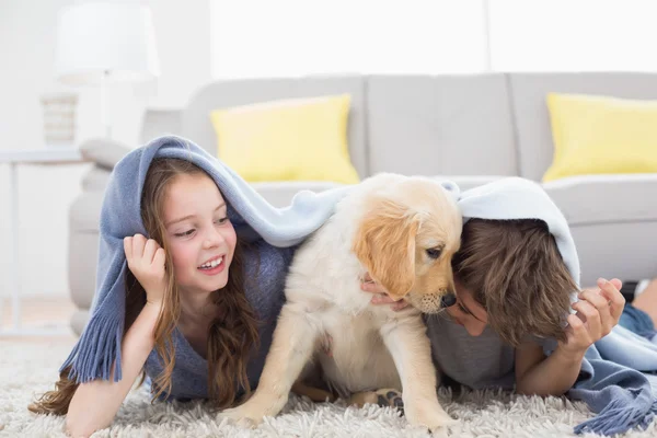 Братья и сестры с щенком под одеялом — стоковое фото
