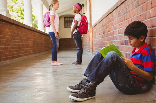 Schoolboy with friends in background at school corridor — Stock Photo, Image