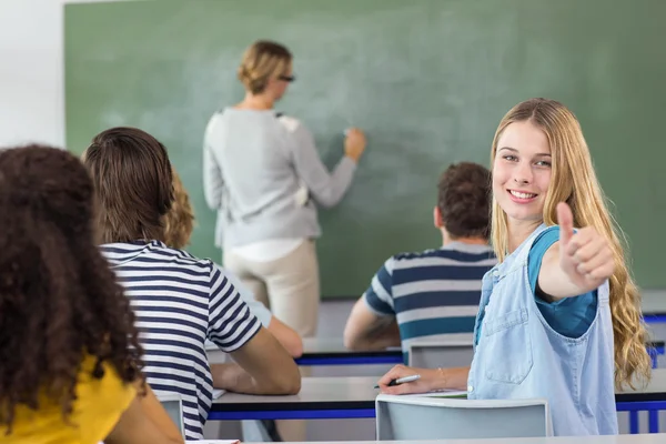 Estudante do sexo feminino gesticulando polegares para cima na classe — Fotografia de Stock