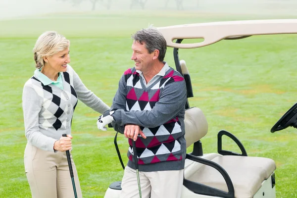 Golfing couple with golf buggy behind — Stock Photo, Image