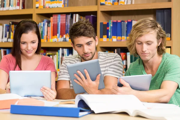 Estudantes universitários usando tablets digitais na biblioteca — Fotografia de Stock