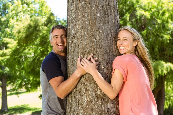 Pareja feliz abrazando un árbol — Foto de Stock