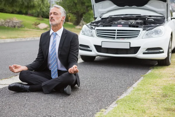 Businessman meditating after his car broken down — Stock Photo, Image