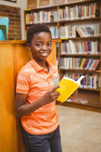 Bonito menino leitura livro na biblioteca — Fotografia de Stock