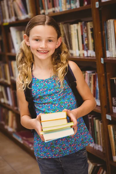 Linda niña sosteniendo libros en la biblioteca —  Fotos de Stock