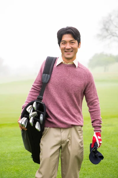 Golfista de pie sosteniendo su bolsa de golf sonriendo a la cámara —  Fotos de Stock