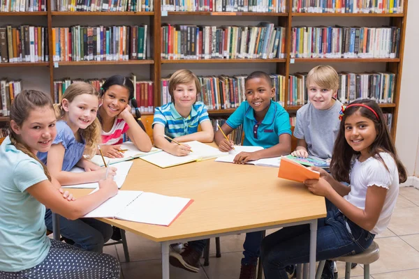 Lindos alumnos escribiendo en el escritorio en la biblioteca —  Fotos de Stock