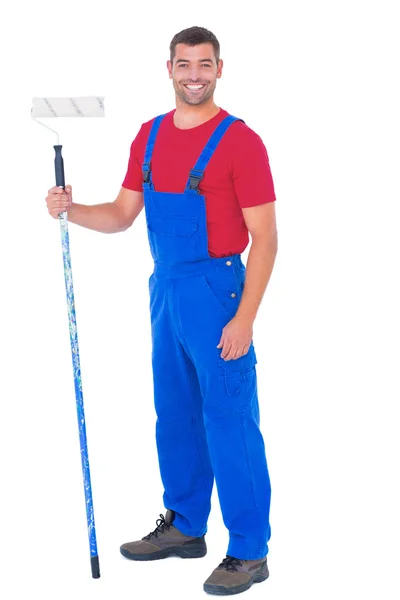 Handyman in overalls holding paint roller — Stock Photo, Image