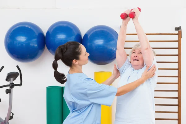 Terapis membantu wanita senior cocok dumbbells — Stok Foto