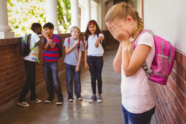 Sad schoolgirl with friends in background at school corridor — Stock Photo, Image