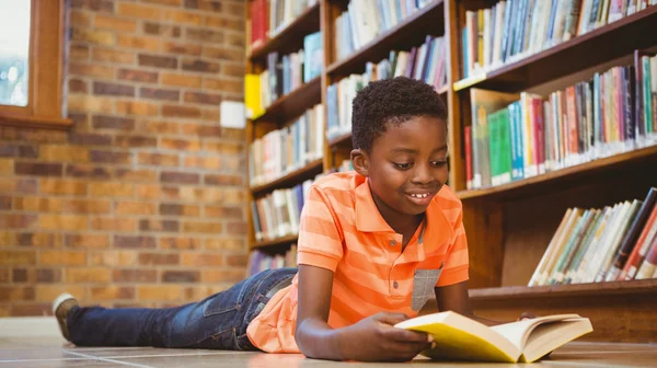 Bonito menino leitura livro na biblioteca — Fotografia de Stock