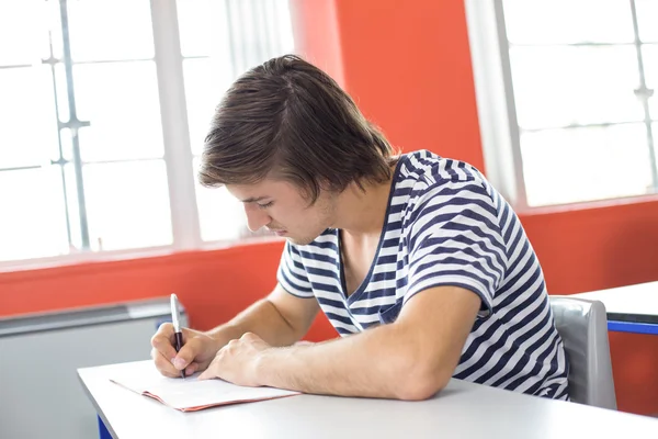 Estudiante masculino escribiendo notas en el aula — Foto de Stock