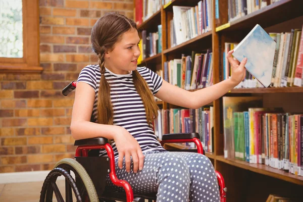 Dziewczyna na wózku inwalidzkim, wybierając książki w bibliotece — Zdjęcie stockowe