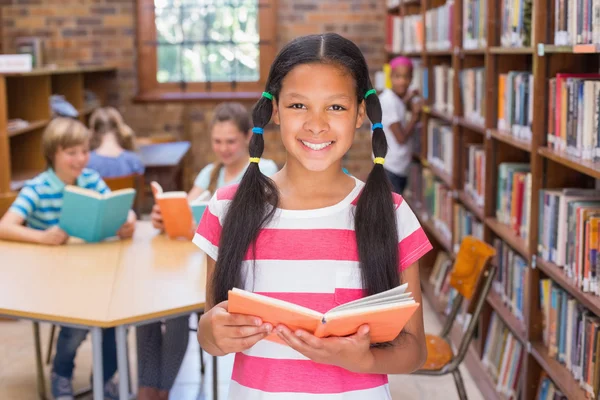 Schattig leerling op zoek naar boeken in bibliotheek — Stockfoto