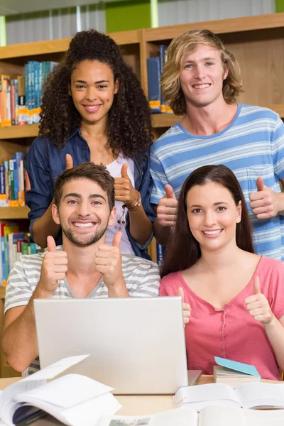 Студенты колледжа жестом вверх в библиотеке — стоковое фото