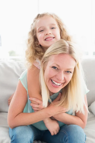 Mamma åker snålskjuts dotter på soffa — Stockfoto