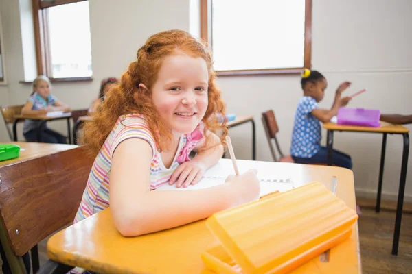 Nette Schüler zeichnen am Schreibtisch, einer lächelt in die Kamera — Stockfoto