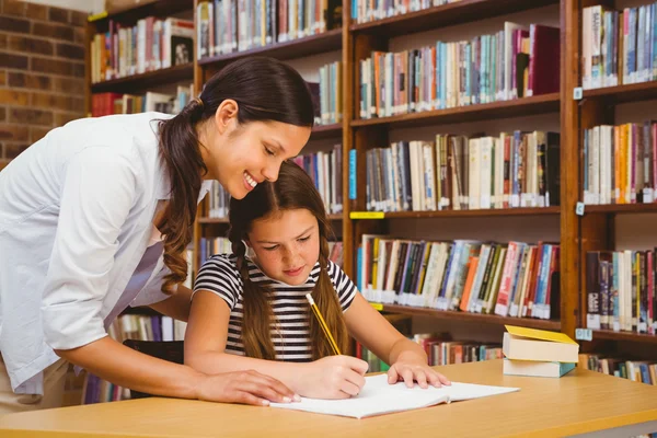 Δάσκαλος βοηθώντας το κορίτσι με τα μαθήματα στη βιβλιοθήκη — Φωτογραφία Αρχείου