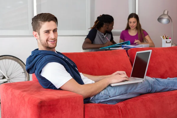 Retrato de homem jovem casual usando laptop no sofá — Fotografia de Stock