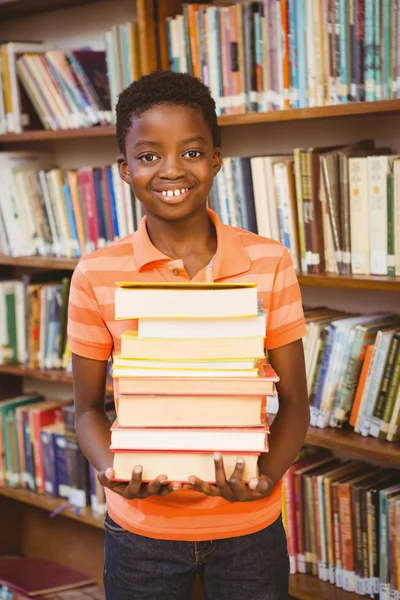 Retrato de menino bonito carregando livros na biblioteca — Fotografia de Stock