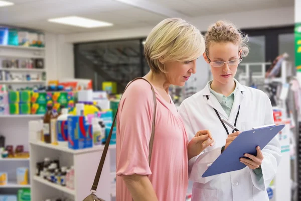 Farmacéutica escribiendo prescripción con su cliente — Foto de Stock