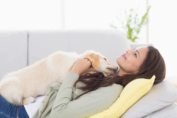 ソファーで横になっている子犬を持つ女性 — ストック写真