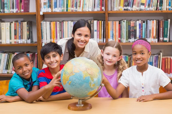 Lindos alumnos y profesores mirando el globo en la biblioteca —  Fotos de Stock