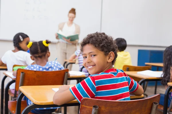 Söt elev ler mot kameran i klassrummet — Stockfoto