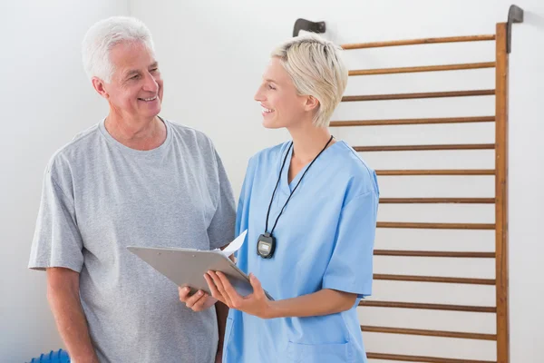Therapist showing clipboard to senior man — Stock Photo, Image
